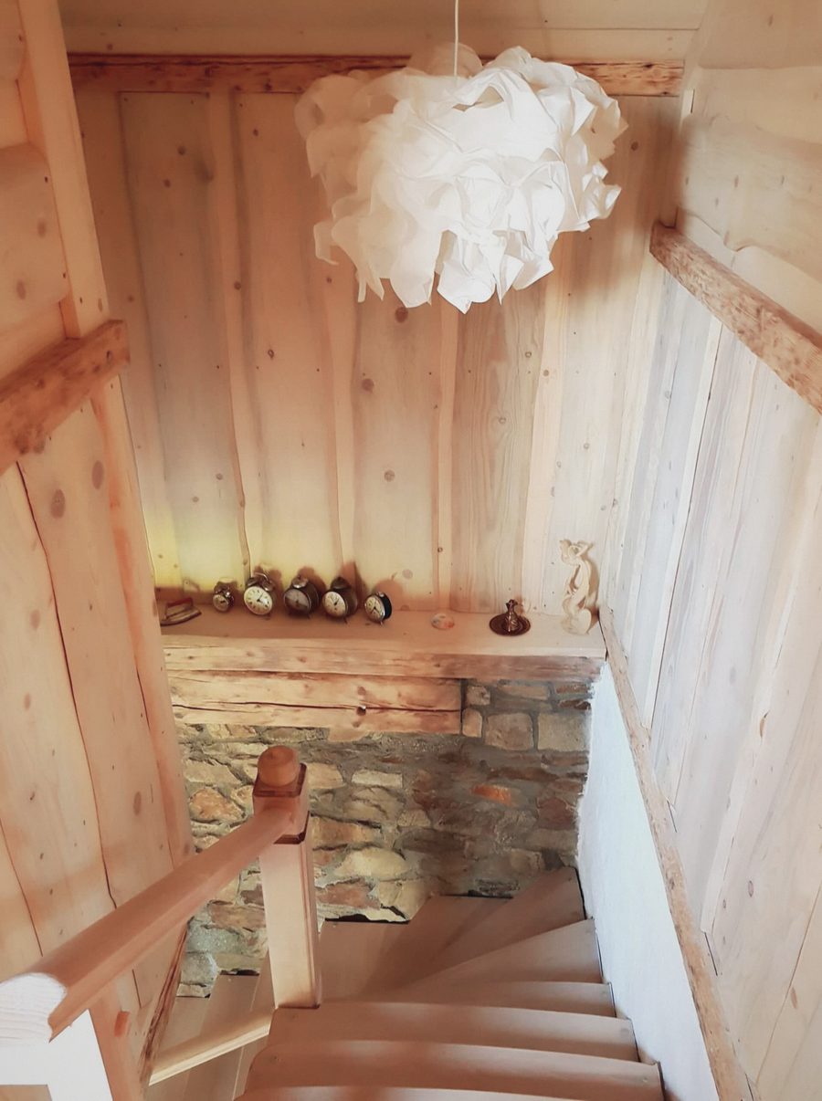 Pohled ze schodů na kamennou zeď a lampu