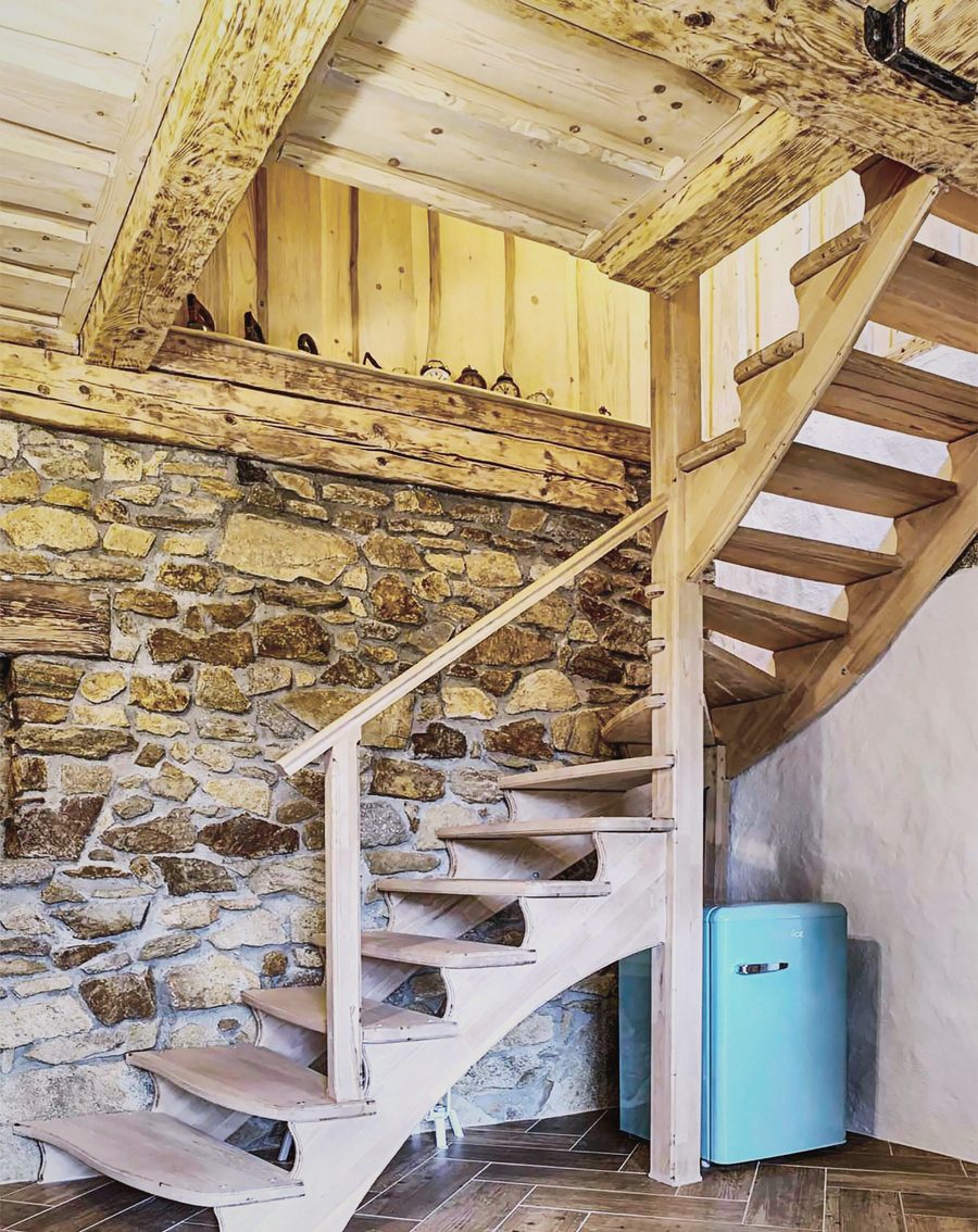 Dřevěné točité schodiště u kamenné zdi a modrá retro lednička